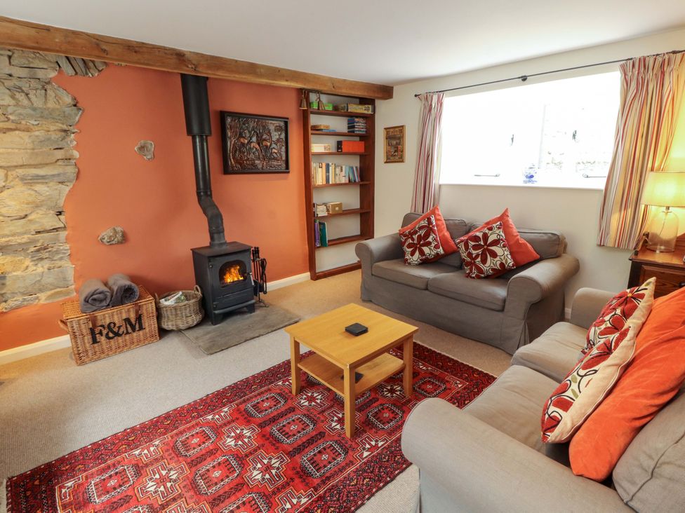 A living room with a stove and bookshelf at One Town End, Mungrisdale, Mosedale