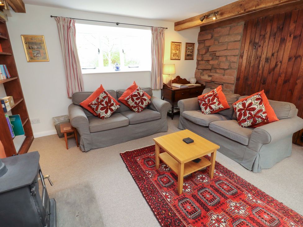 A living room with sofas, coffee table, bookshelves and a window at One Town End, Mungrisdale, Mosedale