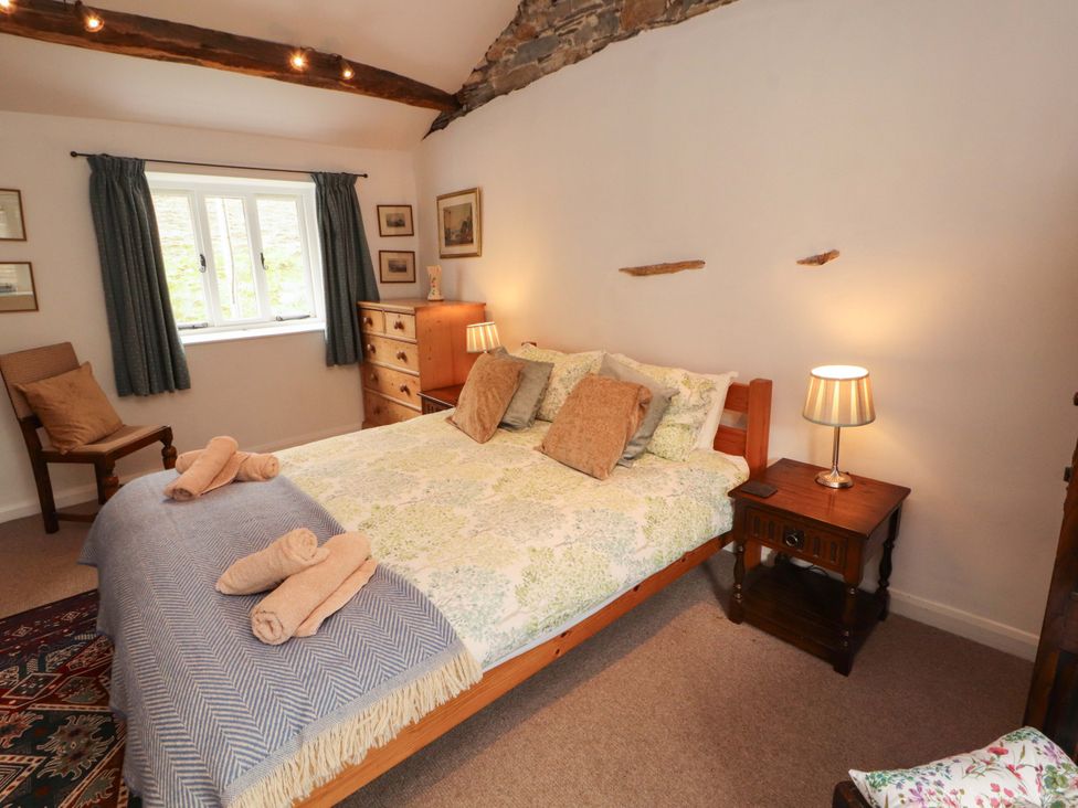 A bedroom with a bed, storage and side table at One Town End, Mungrisdale, Mosedale