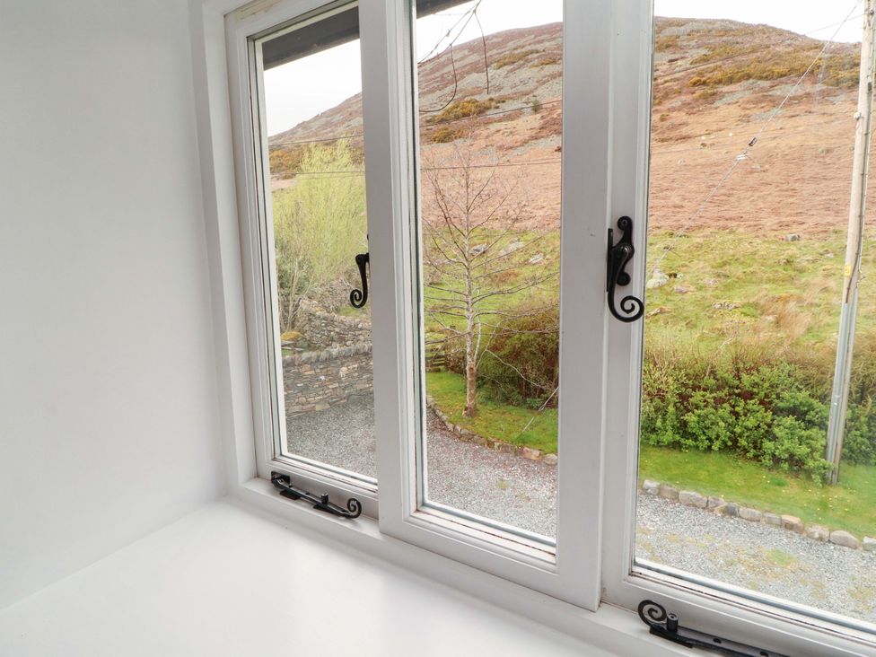A window view showing a gravel area and trees at One Town End in Mungrisdale, Mosedale