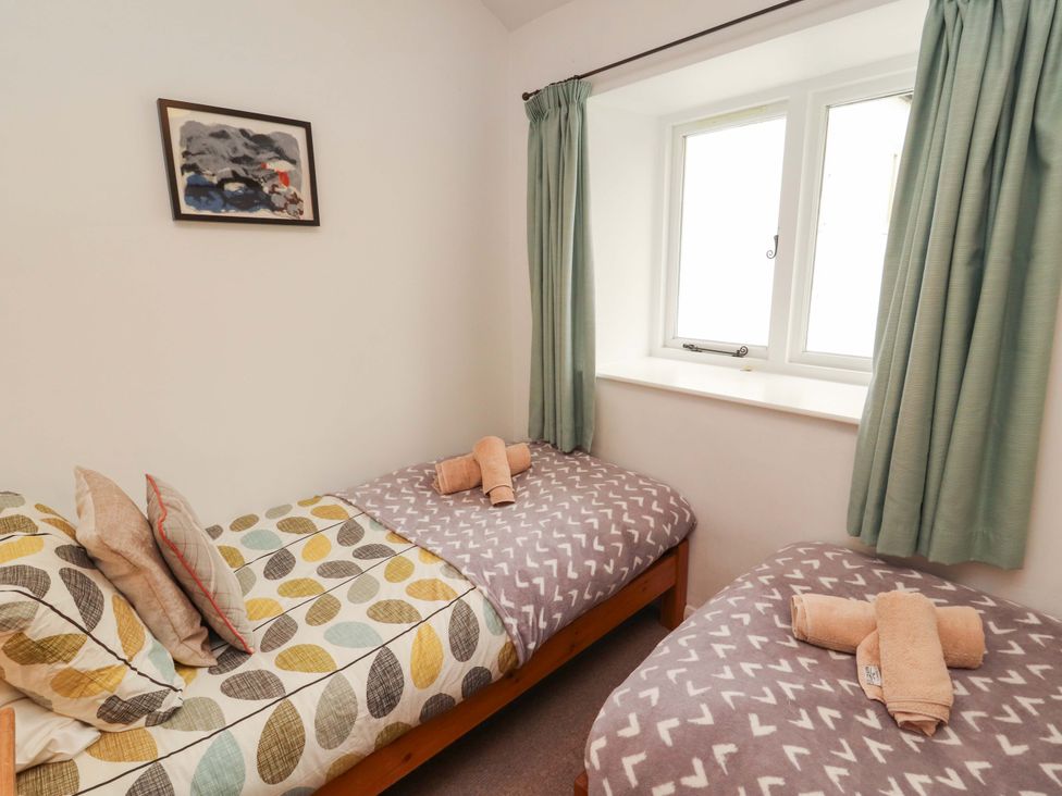 A bedroom with two single beds and a window at One Town End Mungrisdale, Mosedale