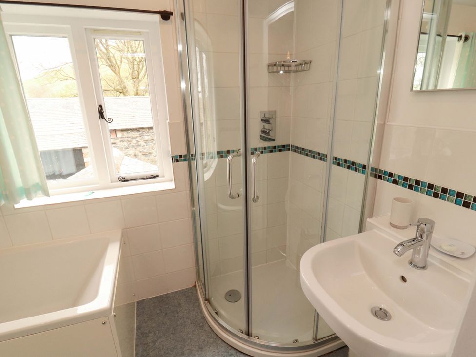 A bathroom with a shower, bathtub, and sink at One Town End, Mungrisdale, Mosedale