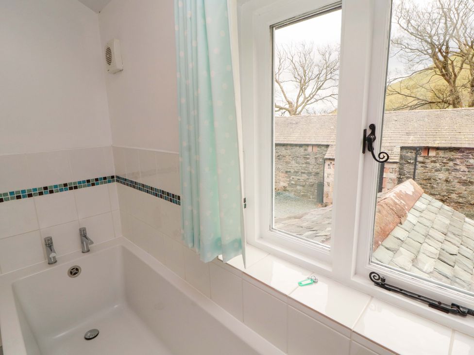 A bathroom with a bathtub and window at One Town End, Mungrisdale, Mosedale