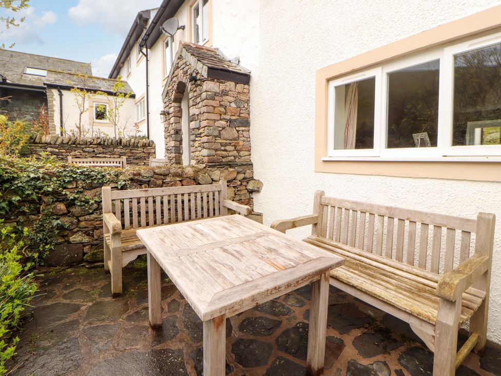 An outdoor area with wooden seating and a table at One Town End, Mungrisdale, Mosedale