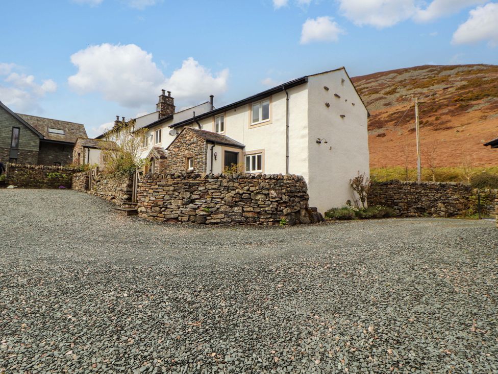 An exterior view of a house with a stone wall and gravel driveway at One Town End, Mungrisdale, Mosedale