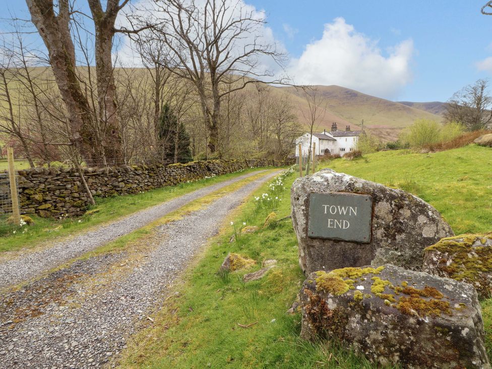 A gravel road leading to Town End with a house and trees at One Town End in Mungrisdale, Mosedale