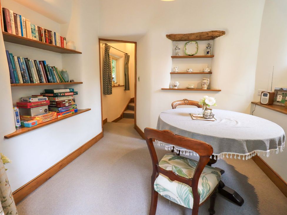 A dining room with bookshelves and a table at Fellside Cottage in Bowness-On-Windermere
