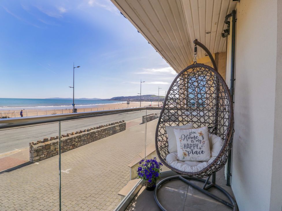 A balcony with a hanging chair and flowers at Ocean View Apartment in Colwyn Bay