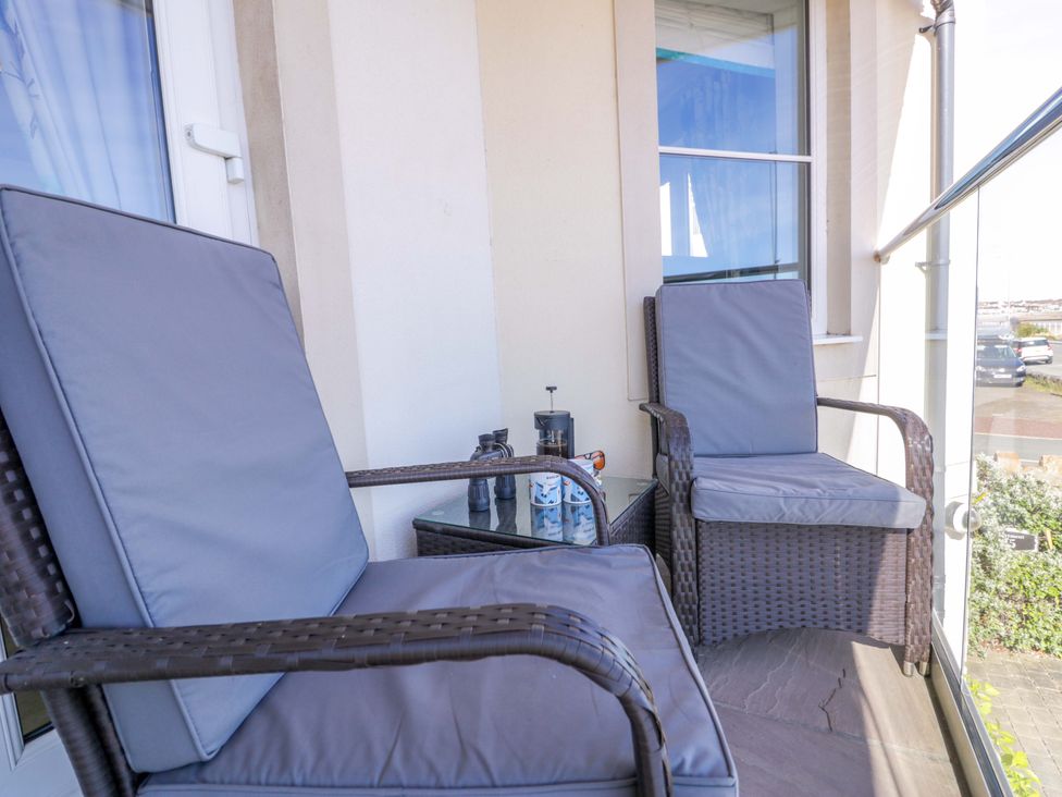 A balcony with two armchairs and a table at Ocean View Apartment in Colwyn Bay