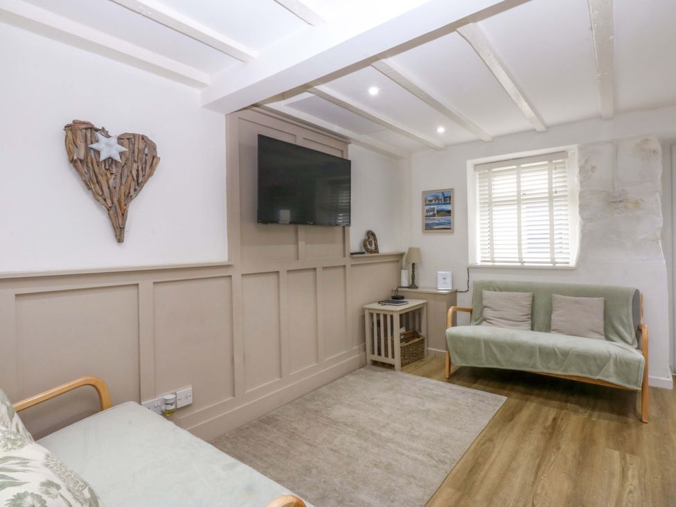 A living room with a television and a wooden heart decoration at 27 Kingshead Street Pwllheli
