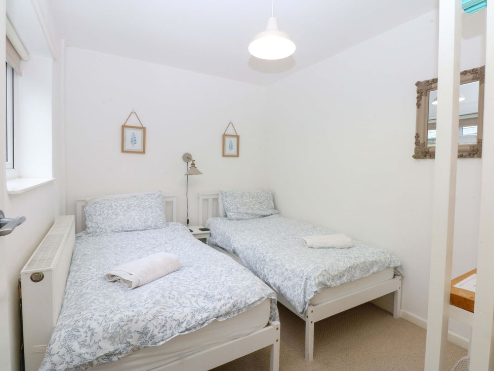 A bedroom with two single beds and a mirror at 27 Kingshead Street Pwllheli