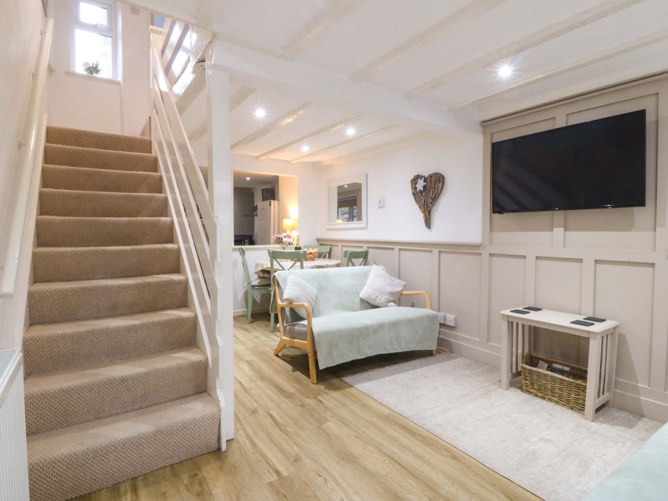 A living room with stairs and a TV at 27 Kingshead Street Pwllheli