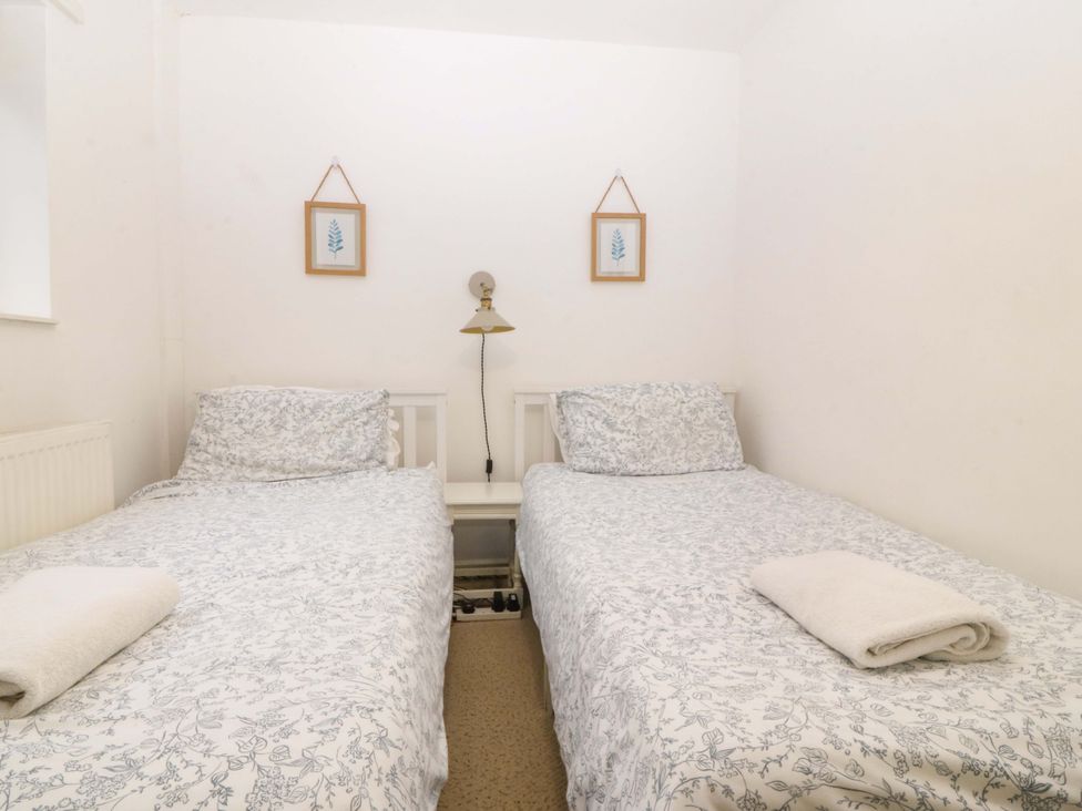 A bedroom with twin beds and a bedside lamp at 27 Kingshead Street Pwllheli