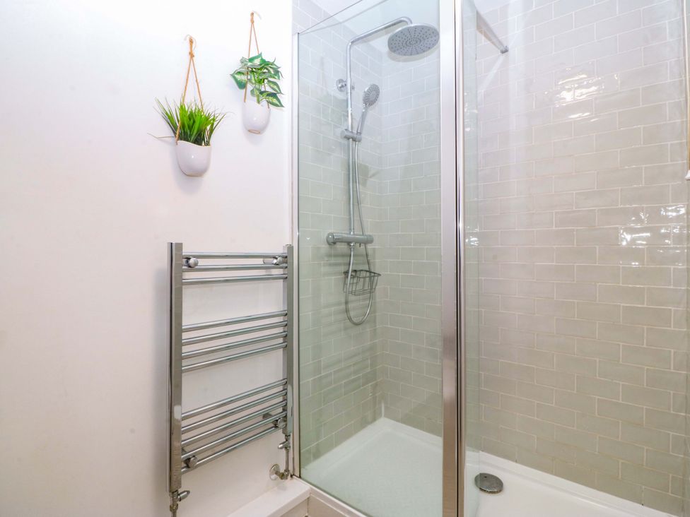 A bathroom with a glass shower and towel radiator at 27 Kingshead Street, Pwllheli