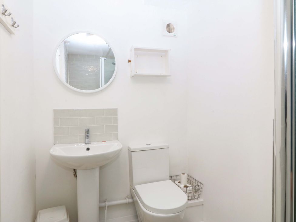 A bathroom with a sink, toilet, and mirror at 27 Kingshead Street Pwllheli