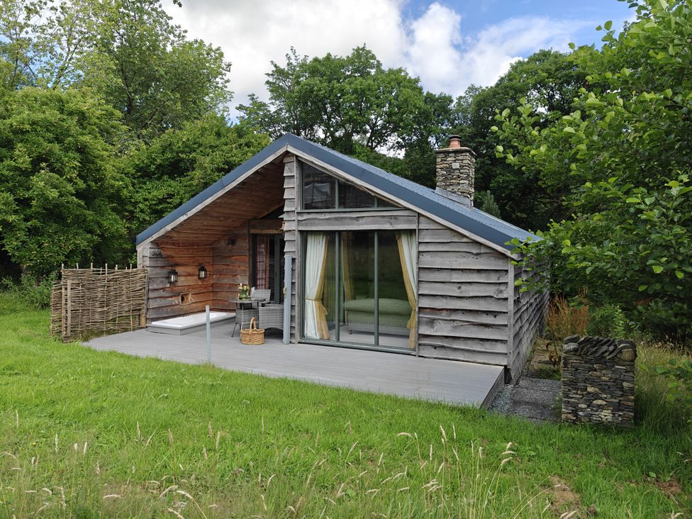 A cabin with a deck and stone chimney at The Hare's Shack in Garnett Bridge, Longsleddale. Near Kendal