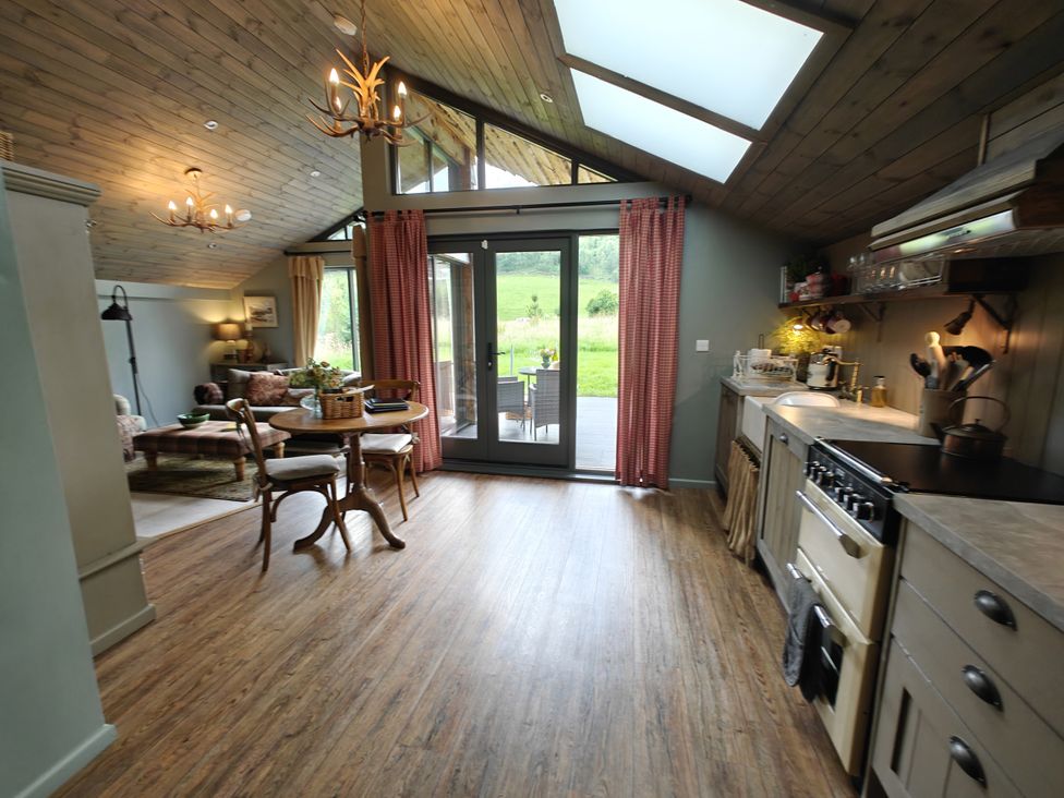 A kitchen with a dining area and open doors to the garden at The Hare's Shack, Garnett Bridge, Longsleddale. Near Kendal