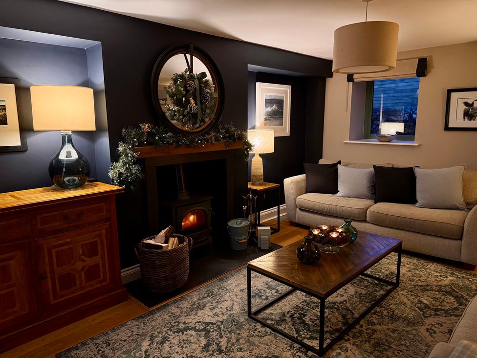 A living room with a sofa, coffee table, and fireplace at Dolwaenydd in Brynsiencyn