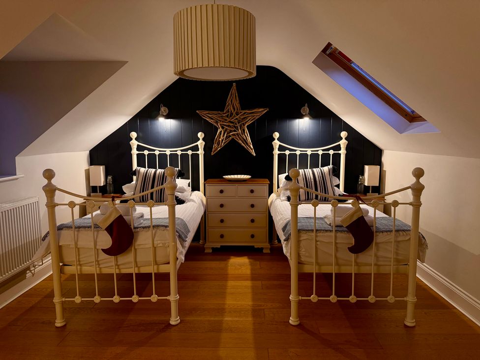 A bedroom with two beds and a dresser at Dolwaenydd in Brynsiencyn