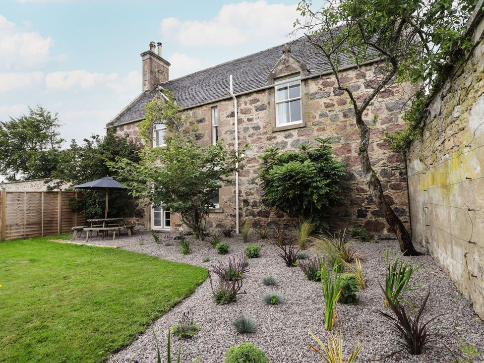 A house with a garden featuring a table and umbrella at Garden House - Brodie Castle in Forres