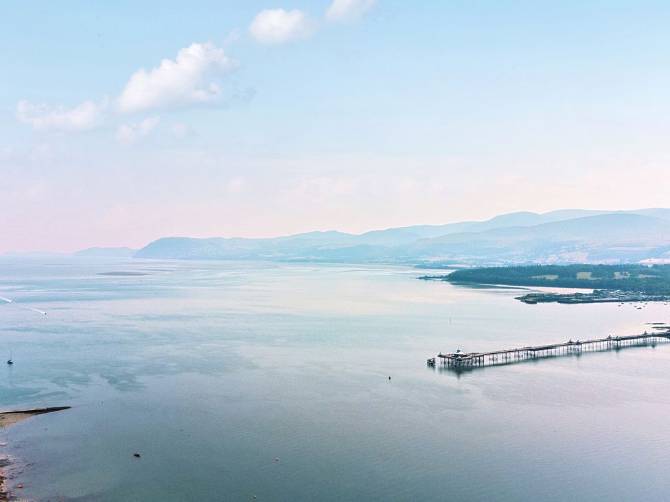 An aerial view of a pier over calm water with mountains in the background at Afallon in Menai Bridge