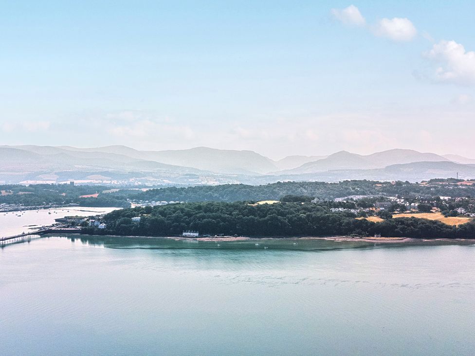 An aerial view of water, land, and mountains at Afallon in Menai Bridge