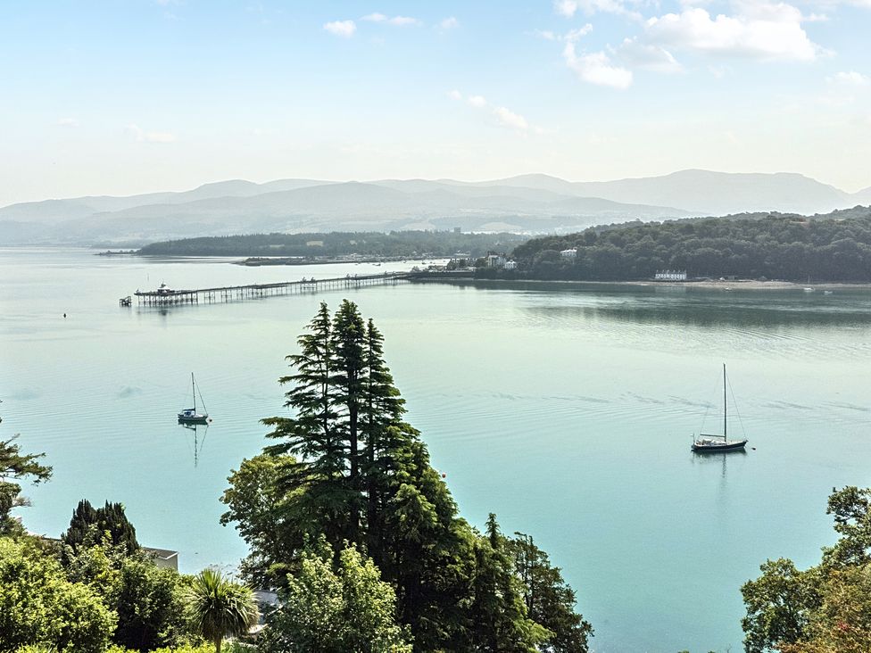 A view of water with trees and a pier at Afallon in Menai Bridge