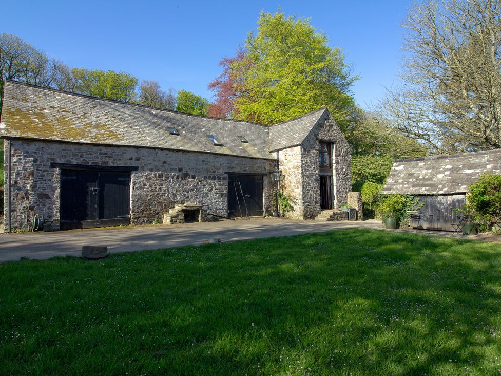 A building with a stone exterior and wooden features at Carrows Stable in Morwenstow