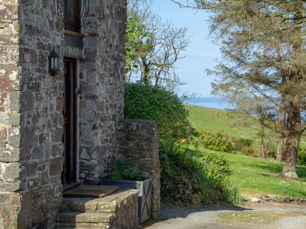 A stone entrance with a door and light fixture at Carrows Stable Morwenstow