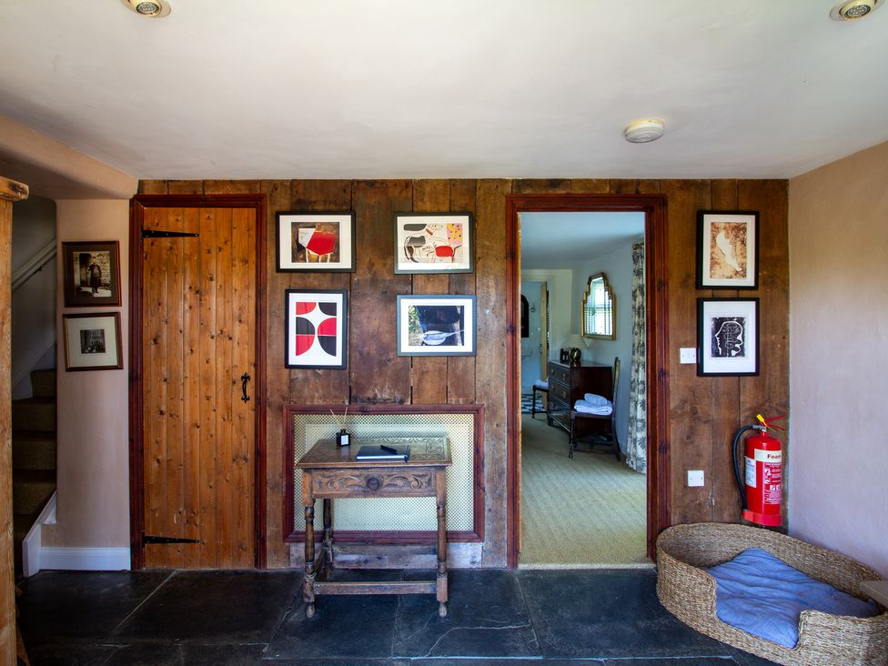 A hallway with wooden walls and photos at Carrows Stable in Morwenstow