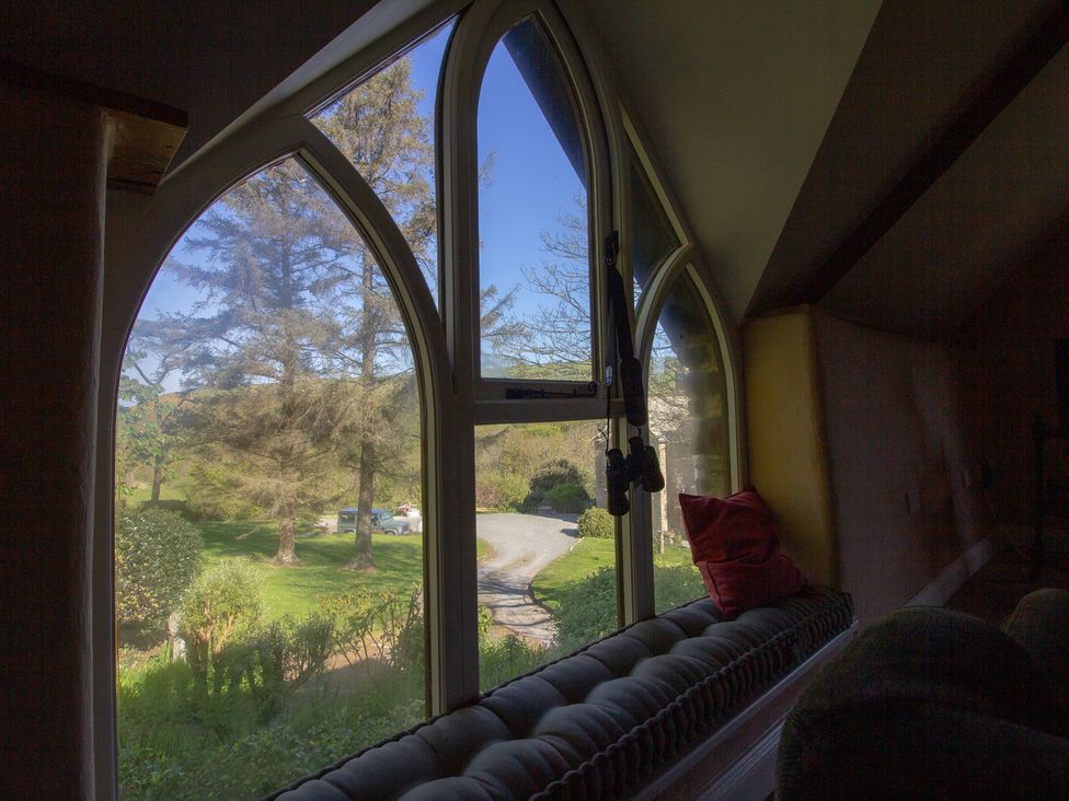 A living room window showing trees and a driveway at Carrows Stable in Morwenstow