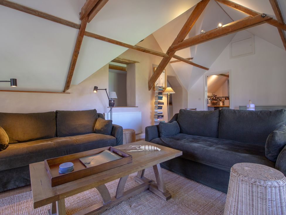 A living room with sofas and a table at Carrows Stable Morwenstow