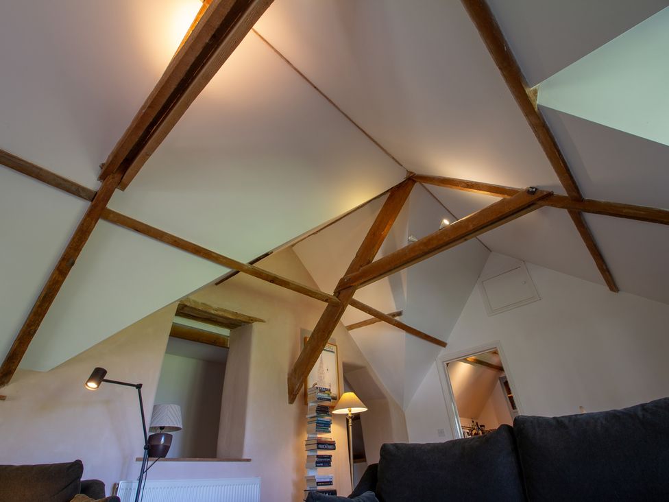 A living room with wooden beams and a lamp at Carrows Stable in Morwenstow