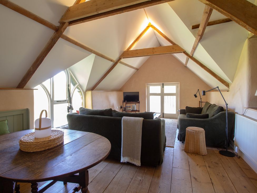 A living room with a sofa and table at Carrows Stable in Morwenstow