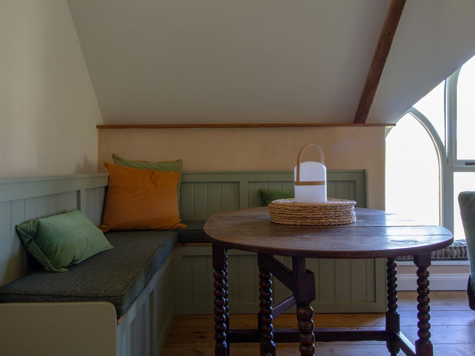 A dining area with a round table and cushions at Carrows Stable in Morwenstow