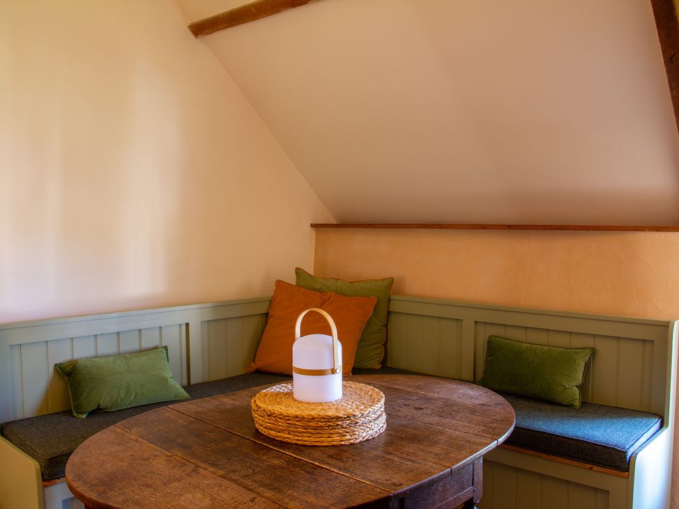 A dining room with a table and cushions at Carrows Stable in Morwenstow