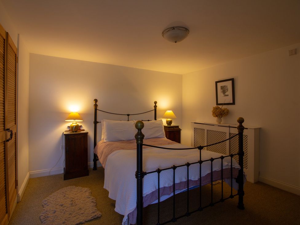 A bedroom with a bed and nightstands at Carrows Stable in Morwenstow
