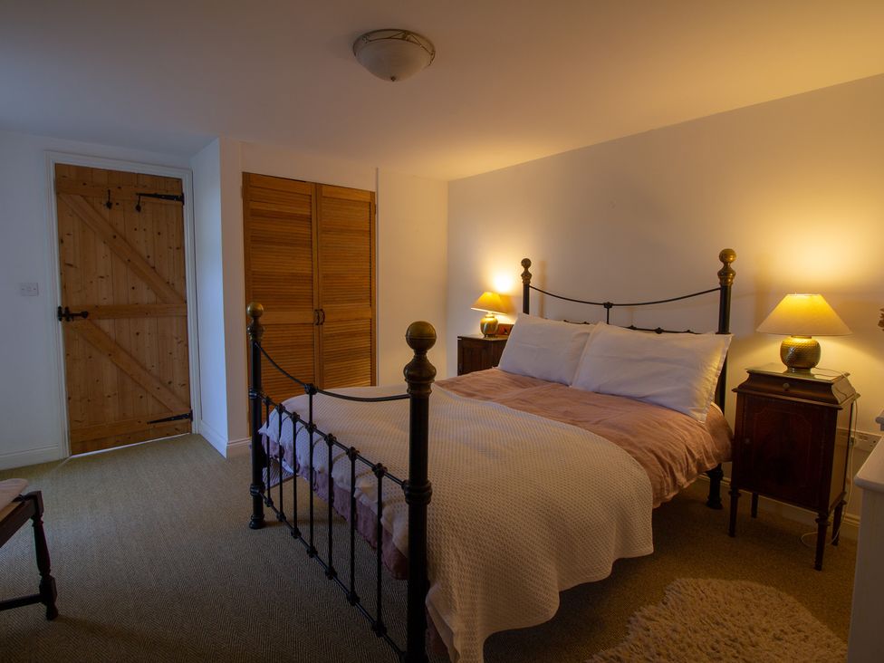 A bedroom with a bed and nightstands at Carrows Stable in Morwenstow