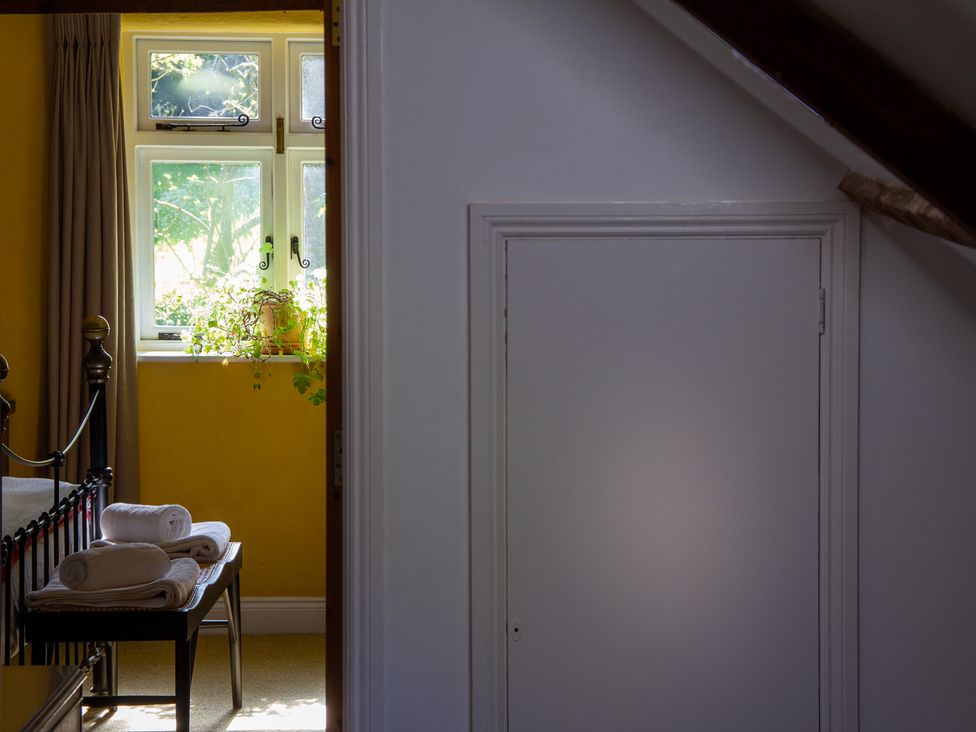 A bedroom with towels on a bed and a window at Carrows Stable in Morwenstow