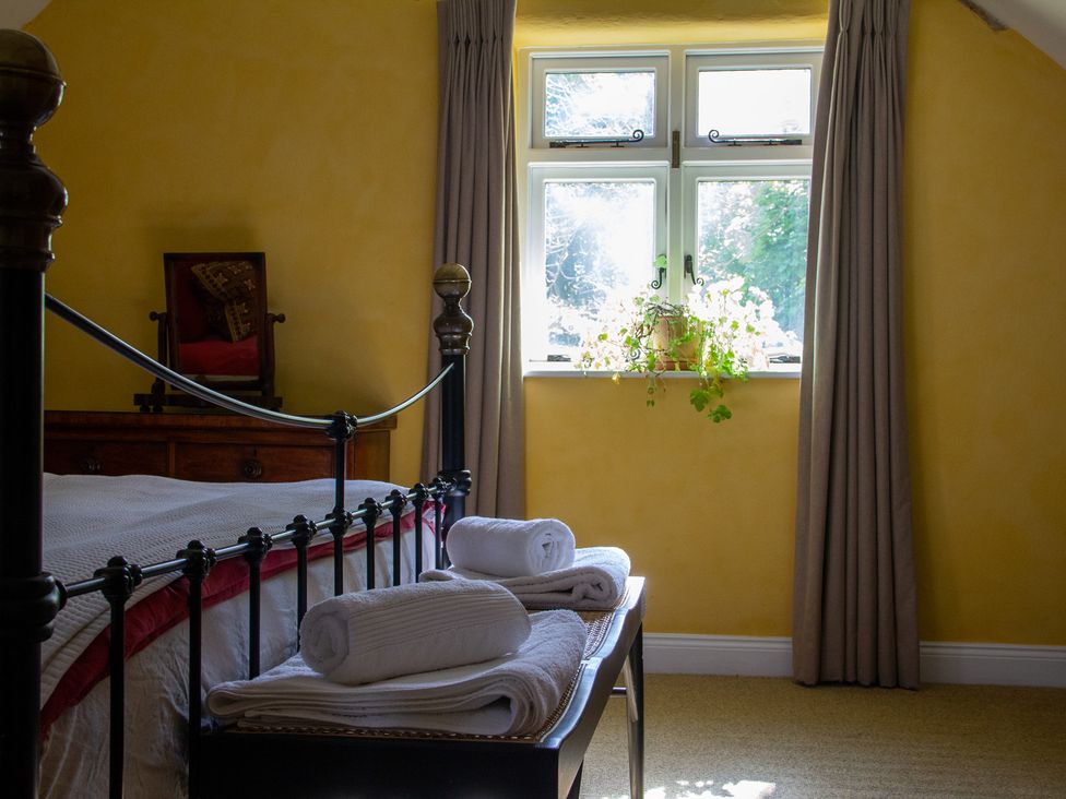 A bedroom with a bed and towels on a bench at Carrows Stable in Morwenstow