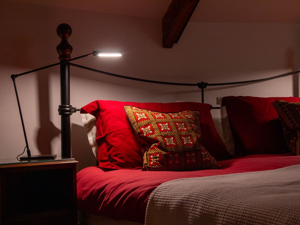 A bed with pillows and a lamp at Carrows Stable in Morwenstow