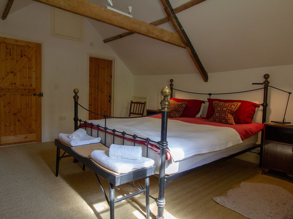 A bedroom with a bed and wooden furniture at Carrows Stable in Morwenstow