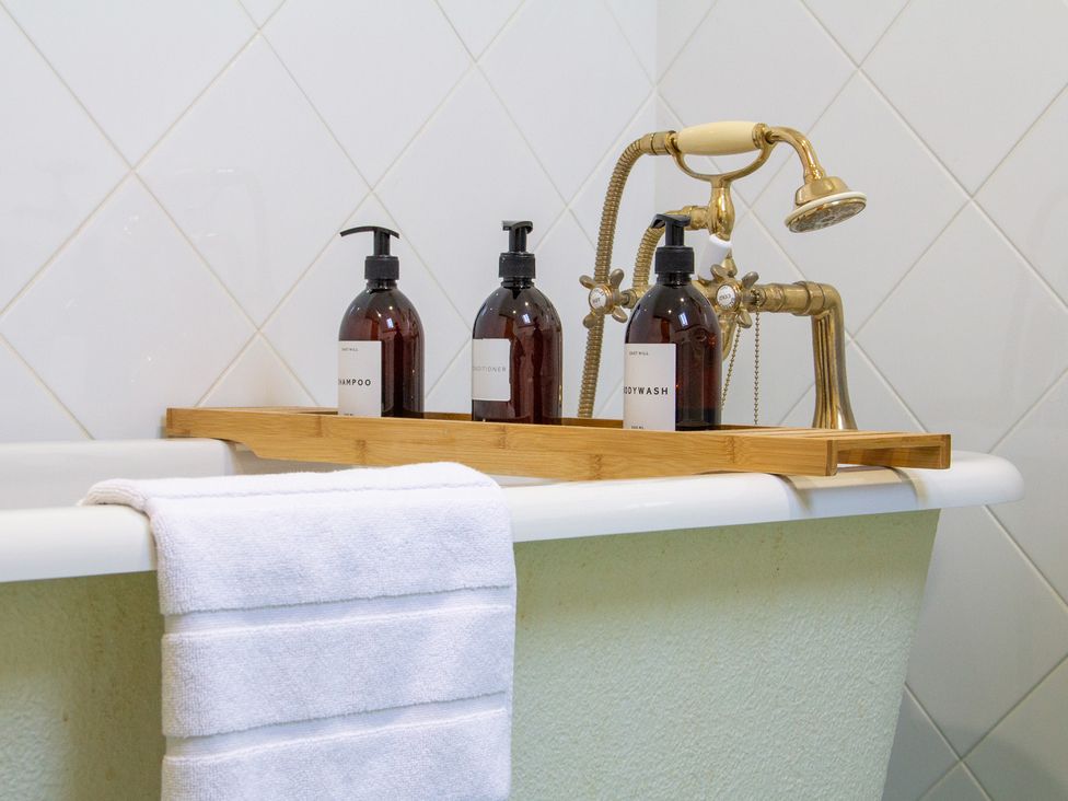 A bathtub with shampoo, conditioner, and bodywash at Carrows Stable Morwenstow