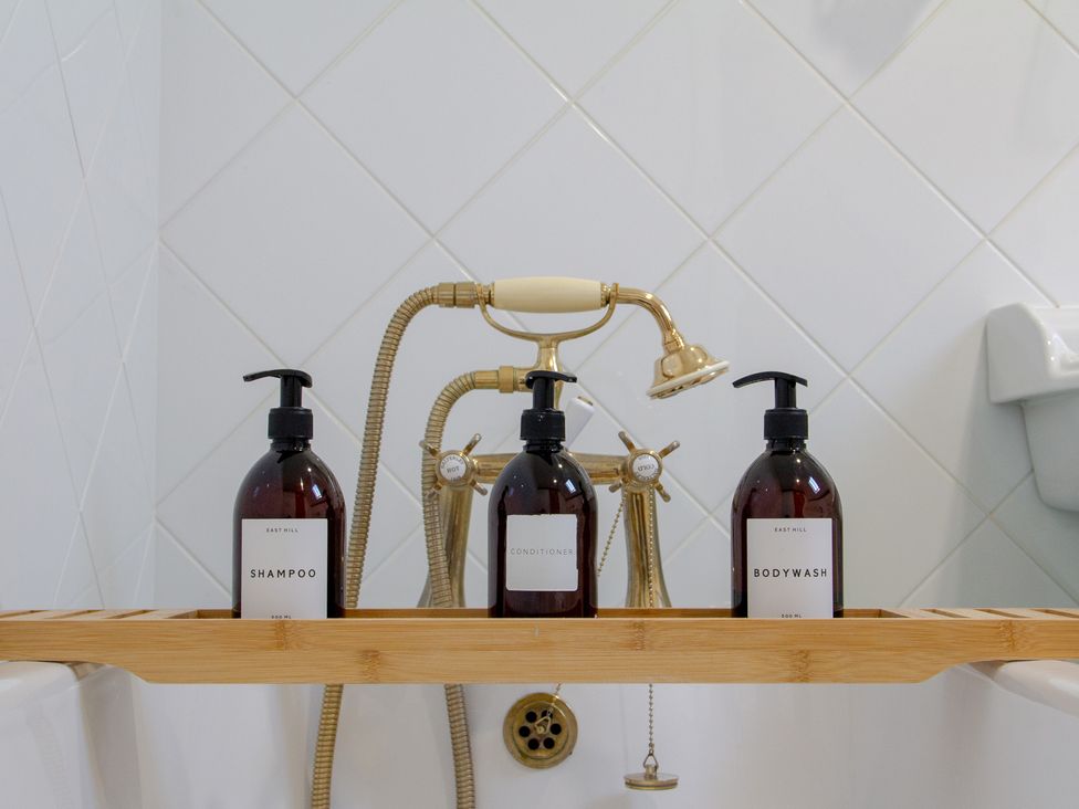 A bathtub with shampoo, conditioner, and bodywash at Carrows Stable in Morwenstow