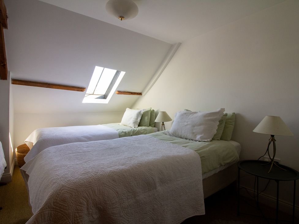 A bedroom with two beds and a window at Carrows Stable Morwenstow