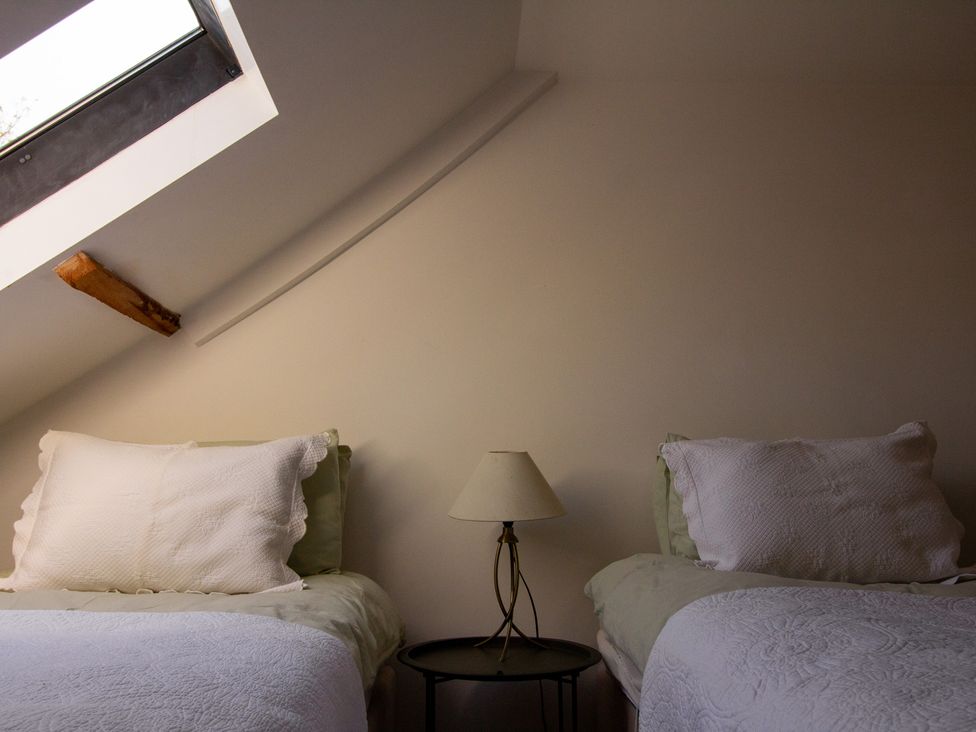 A bedroom with two beds and a lamp at Carrows Stable in Morwenstow