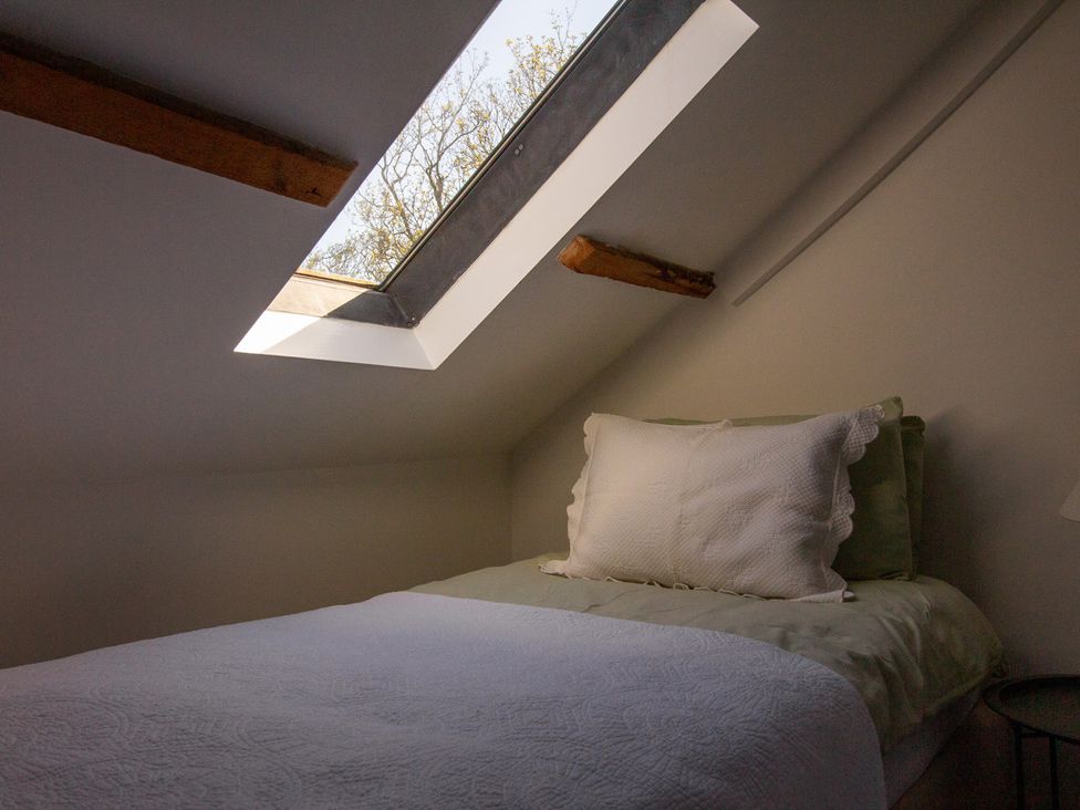 A bedroom with a bed and a skylight at Carrows Stable in Morwenstow