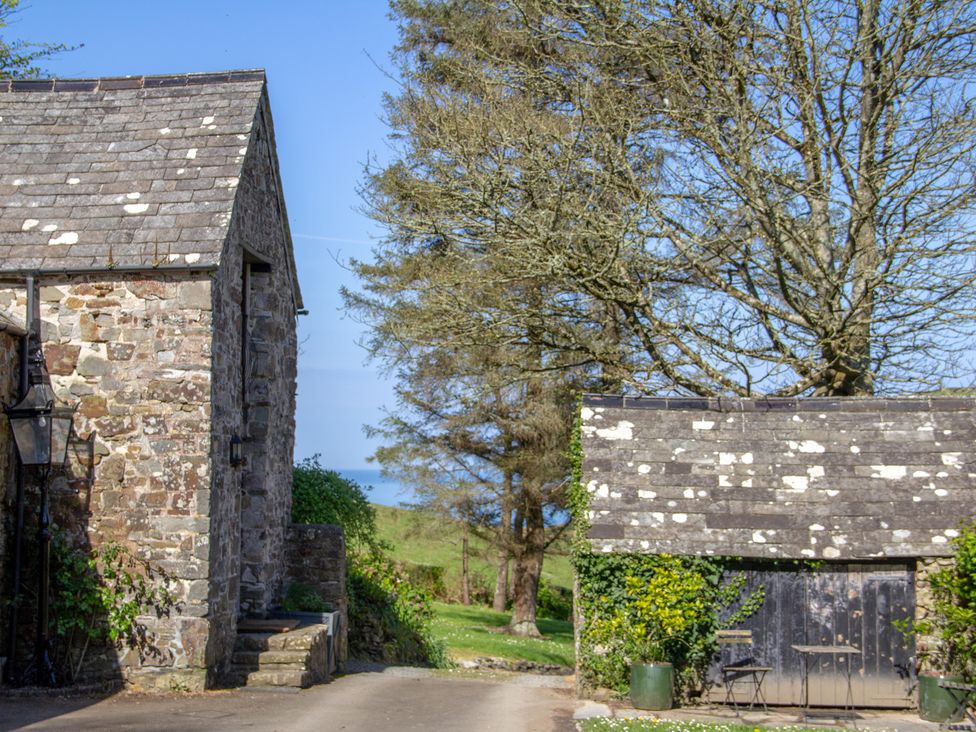 An outdoor view of stone buildings and trees at Carrows Stable Morwenstow