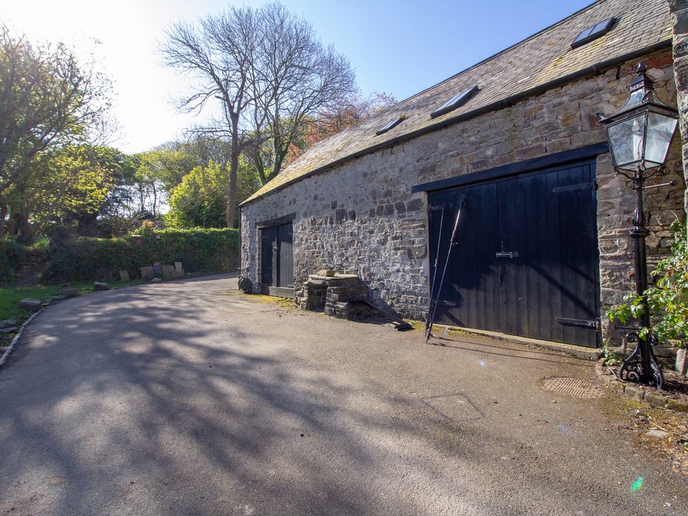 An outdoor photo of a stone building with black doors at Carrows Stable Morwenstow