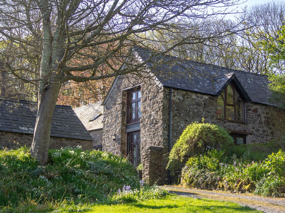 A stone house with windows and grass in front at Carrows Stable in Morwenstow